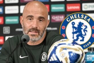 Enzo Maresca in a press conference with the Chelsea badge.